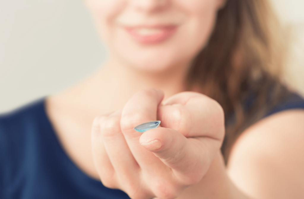 A woman holds out a contact lens on her index finger
