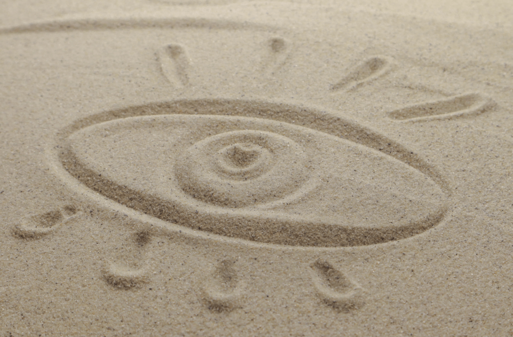 An eye drawn into some sand to describe the feeling of dry and gritty eyes