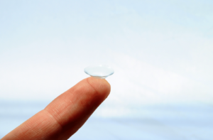 A person holds a contact lens on their index finger.
