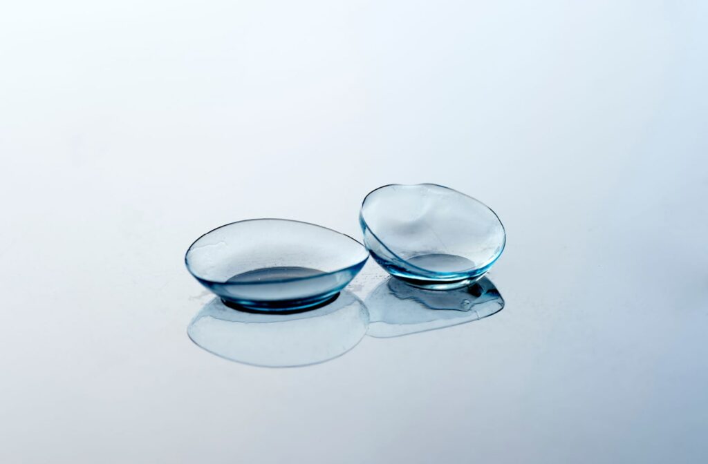 A pair of contact lenses on a reflective surface. The left lens is new and in good condition, while the right lens is expired and degraded