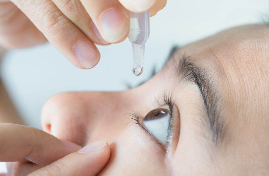 A close-up shot of a young woman applying eye drops as a treatment for dry eyes.