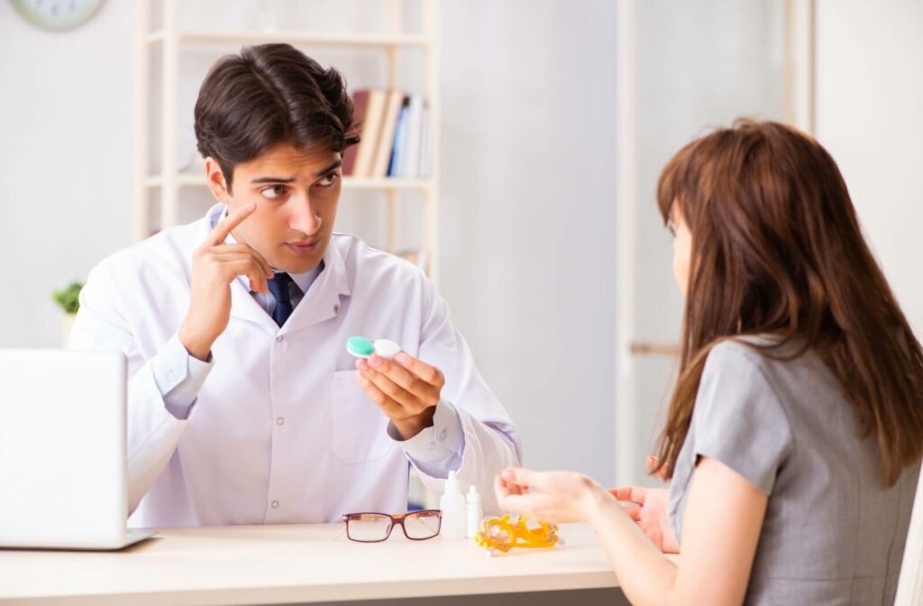 A male optometrist explaining to a young woman how to use her new contacts at his office desk