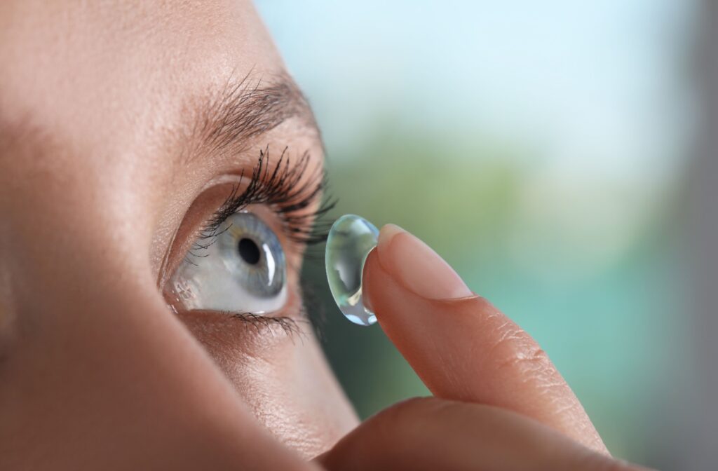 A close-up image of a woman with a scleral contact lens on the tip of her finger.