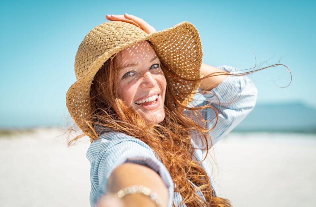 Woman smiling at the beach, enjoying clear vision with new scleral lenses for keratoconus.