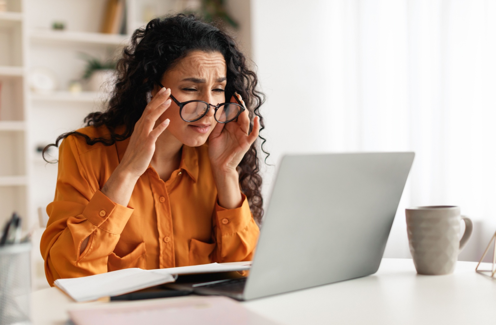 A person struggles to see their laptop screen clearly even with their glasses.