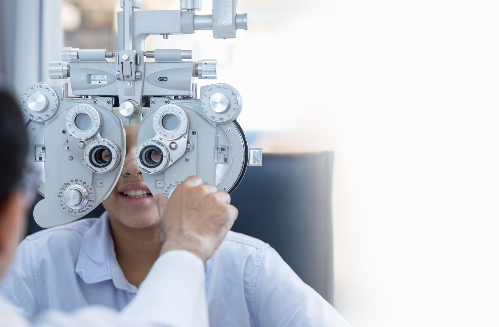 An optometrist adjusts a patient's phoropter during their routine eye exam.